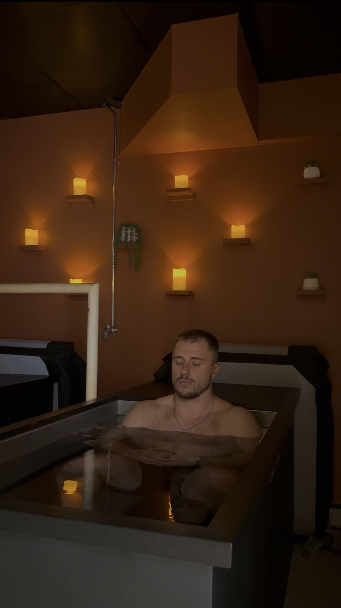 Ryan breathing calmly in a cold plunge lit by candles